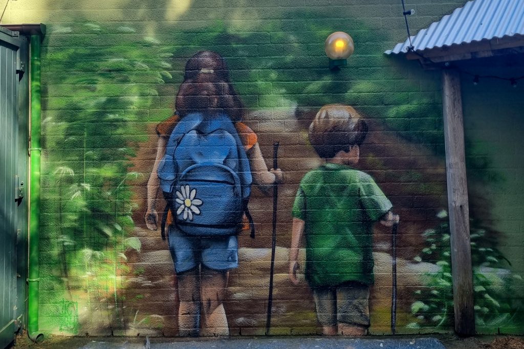 Graffiti/muurschildering van 2 wandelende kinderen in de natuur